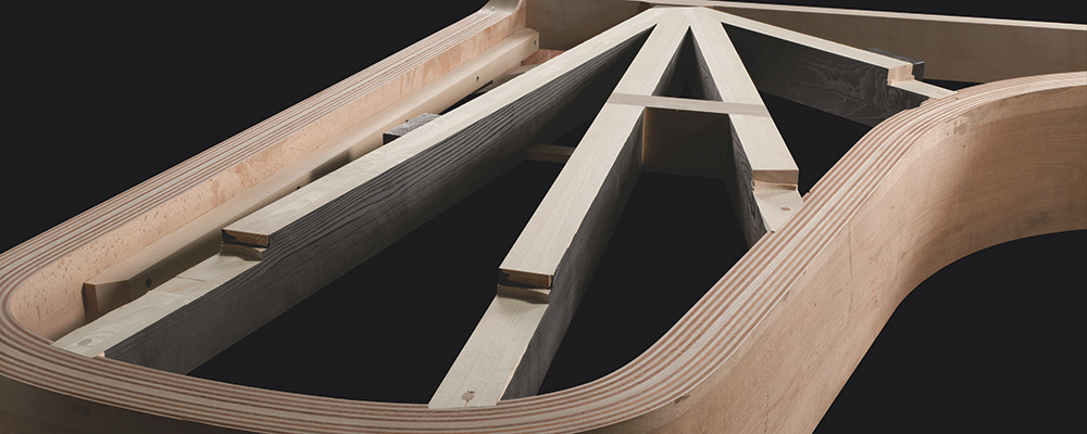 A view of the back beam and posts where they meet the frame on an unfinished piano.